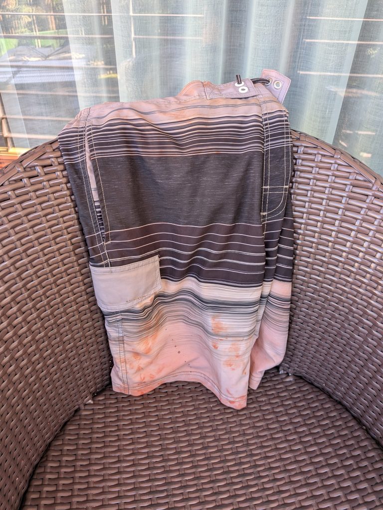 A pair of formerly navy and white swim shorts that are now permanently discolored and pinkish as a result of rust