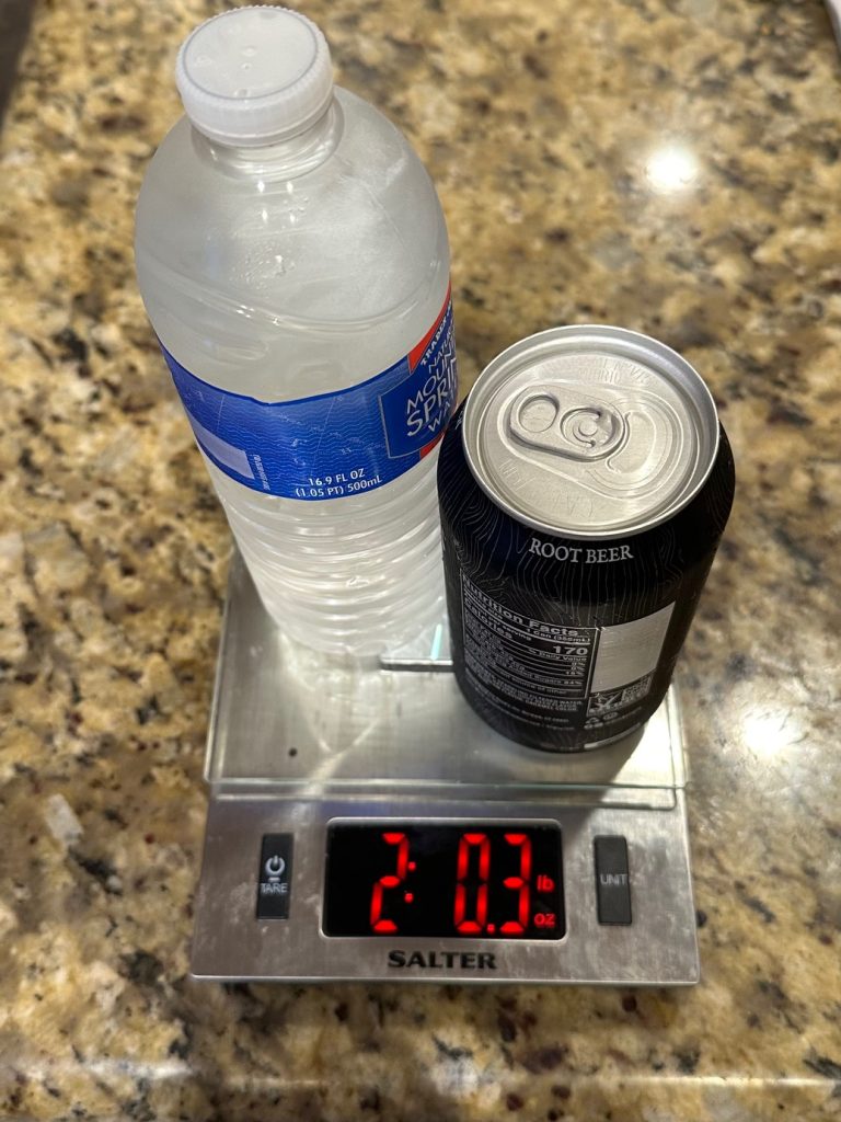 A frozen water bottle and can of soda on a kitchen scale weight in at about 2 pounds